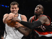 Brooklyn Nets' Kris Humphries, left, and Portland Trail Blazers' J.J. Hickson battle for the ball in the third quarter Sunday.