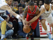 Portland Trail Blazers guard Damian Lillard, center, battles for control of a loose ball with Denver Nuggets forward JaVale McGee, left, and guard Evan Fournier.