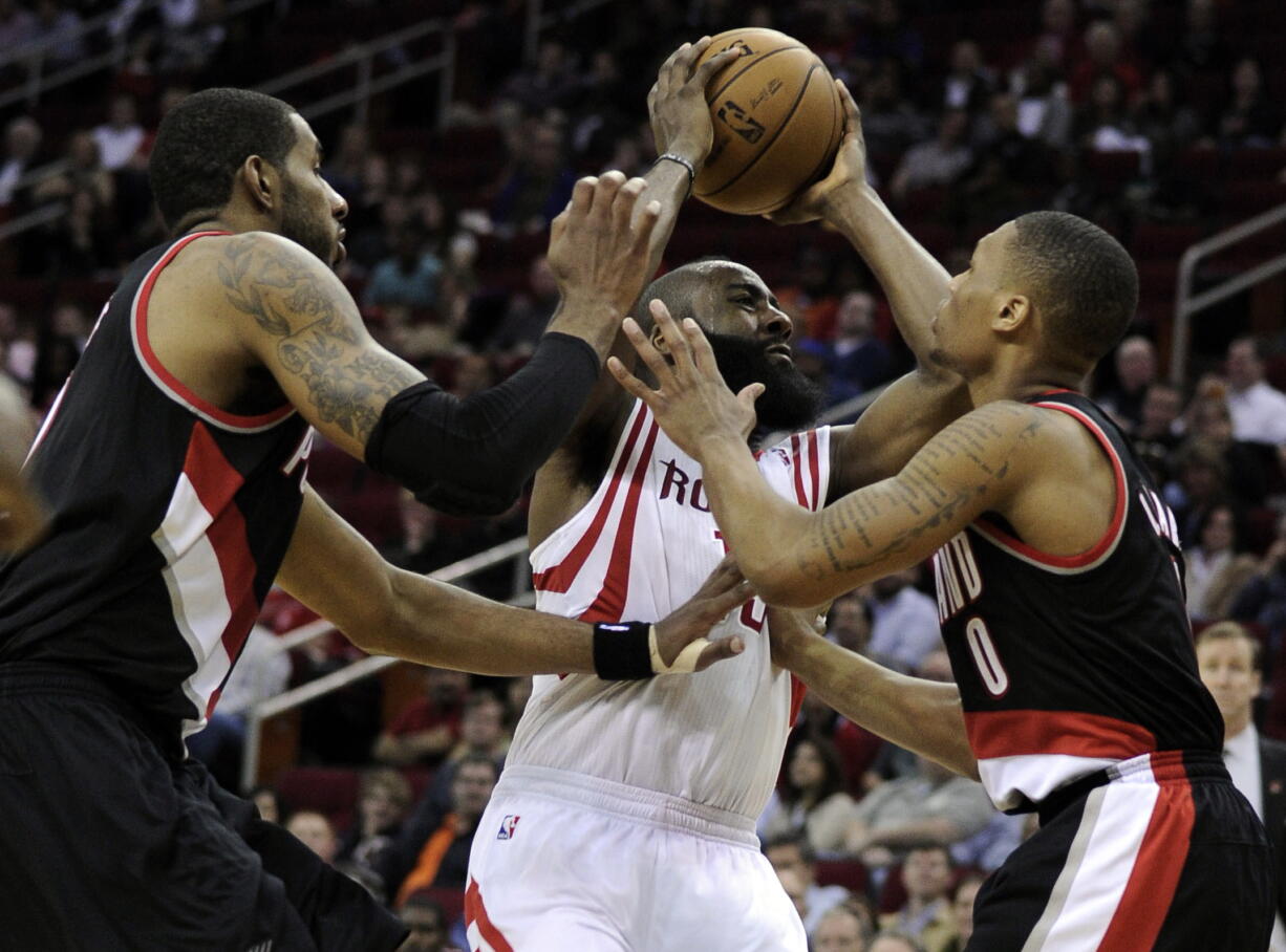 Houston Rockets' James Harden, center, is sandwiched between Portland Trail Blazers Damian Lillard (0) and LaMarcus Aldridge in the second half Friday.