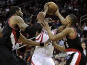 Houston Rockets' James Harden, center, is sandwiched between Portland Trail Blazers Damian Lillard (0) and LaMarcus Aldridge in the second half Friday.