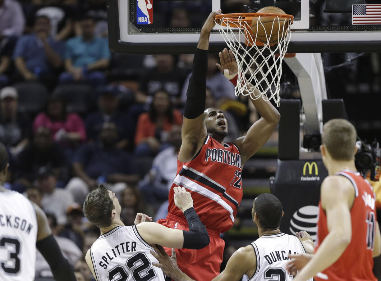 Portland Trail Blazers' LaMarcus Aldridge (12) scores over San Antonio Spurs' Tiago Splitter (22), of Brazil, and Tim Duncan, right, during the first half of an NBA basketball game on Friday, March 8, 2013, in San Antonio.