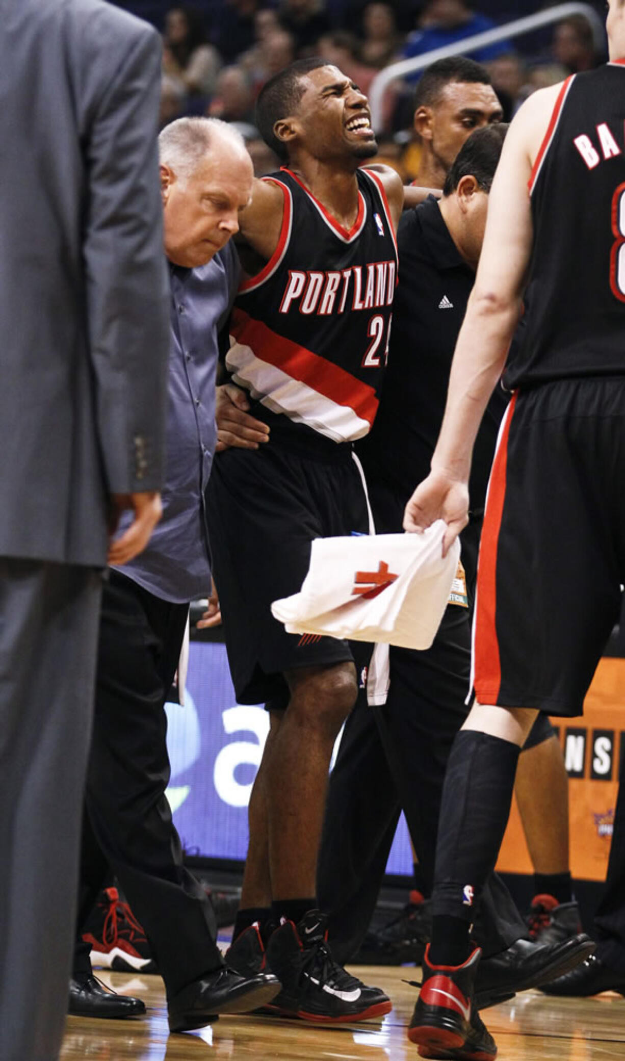 Portland's Ronnie Price grimaces as he is helped off the court in Phoenix after rolling his ankle on Friday.