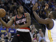 Portland Trail Blazers' Wesley Matthews, left, looks to pass away from Golden State Warriors' Festus Ezeli during the first half Saturday.