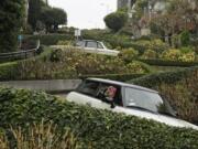 A woman takes a selfie while riding down the crooked section of Lombard Street in San Francisco. The section of eight hairpin turns, one-way, downhill, starts at Hyde Street.