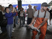 Justin Hall throws a salmon to a co-worker behind the counter at Pike Place Fish at Pike Place Market in Seattle.