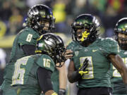 Oregon running back Byron Marshall, right, celebrates his touchdown with teammates Daryle Hawkins (16) and quarterback Marcus Mariota (8) during the second half of an NCAA college football game against UCLA in Eugene, Ore., Saturday, Oct. 26, 2013. Marshall ran for 133 yards and three touchdowns for a 42-14 victory.