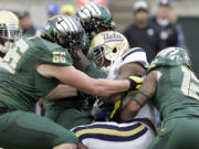 UCLA running back Paul Perkins, middle, is wrapped up by Oregon defenders Taylor Hart, left, and Brian Jackson during the first half of an NCAA college football game in Eugene, Ore., Saturday, Oct. 26, 2013.