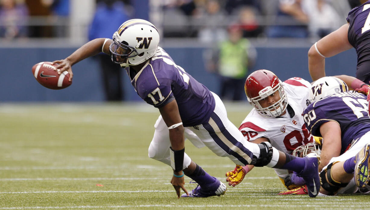 Washington quarterback Keith Price (17) flicks off a pass under pressure against Southern California during the first half Saturday.