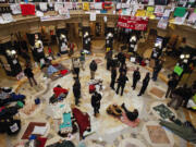 This Feb. 28, 2011 file photo shows protests continuing at the state Capitol in Madison, Wis., as police and demonstrators gather on the rotunda floor where opponents to the governor's bill to eliminate collective bargaining rights for many state workers had been sleeping.