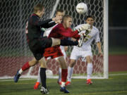 Union's Tyler Shadix, left, strikes the ball away from Roosevelt goalkeeper Julien Leveque on a free kick by Union's Mitch Wheelon for the first goal of the Titans' 2-1 Class 3A state semifinal victory Friday night in Puyallup.