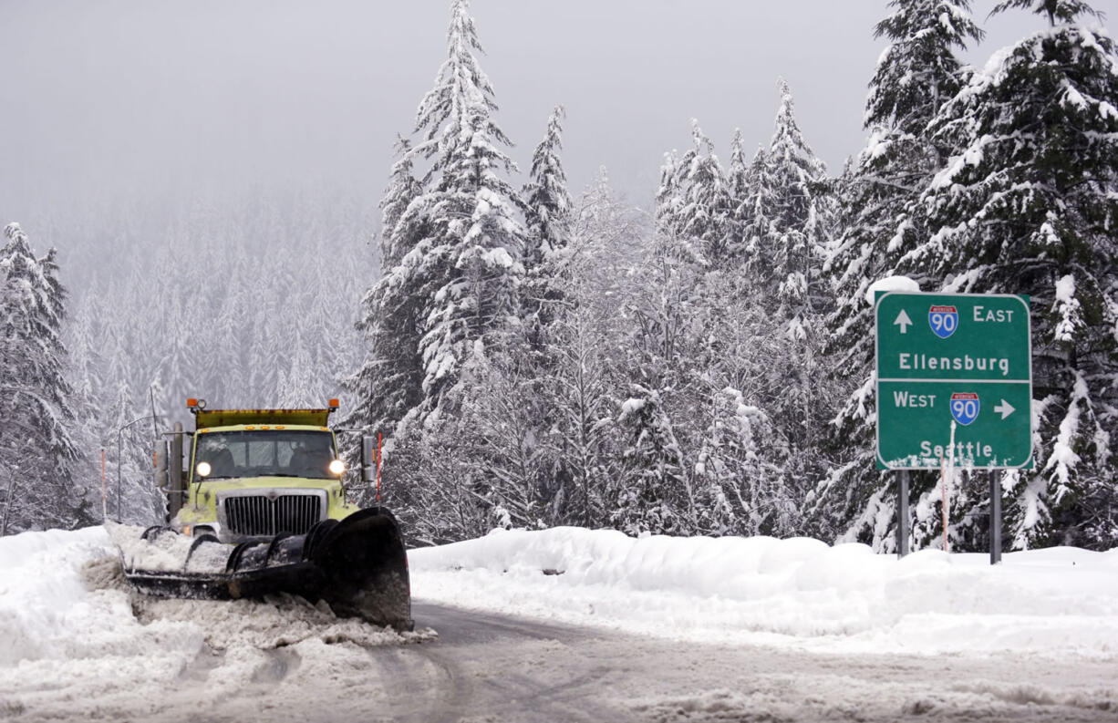 A snowplow clears an overpass of freshly-fallen snow over Interstate 90 at Snoqualmie Pass on Tuesday.