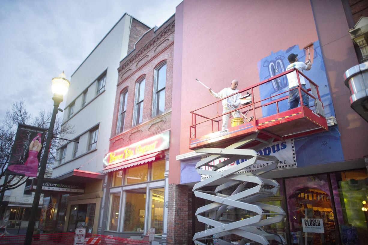 A painting crew works to cover the Inland Octopus toy store mural on Main Street in Walla Walla on Thursday.