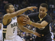 Golden State Warriors' Stephen Curry, right, drives against Milwaukee Bucks' Michael Carter-Williams, left, during the first half of an NBA basketball game Saturday, Dec. 12, 2015, in Milwaukee.