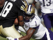 Washington's Sean Parker, right, stops Colorado punt returner Donta Abron in the second quarter of the Huskies' win on Saturday.