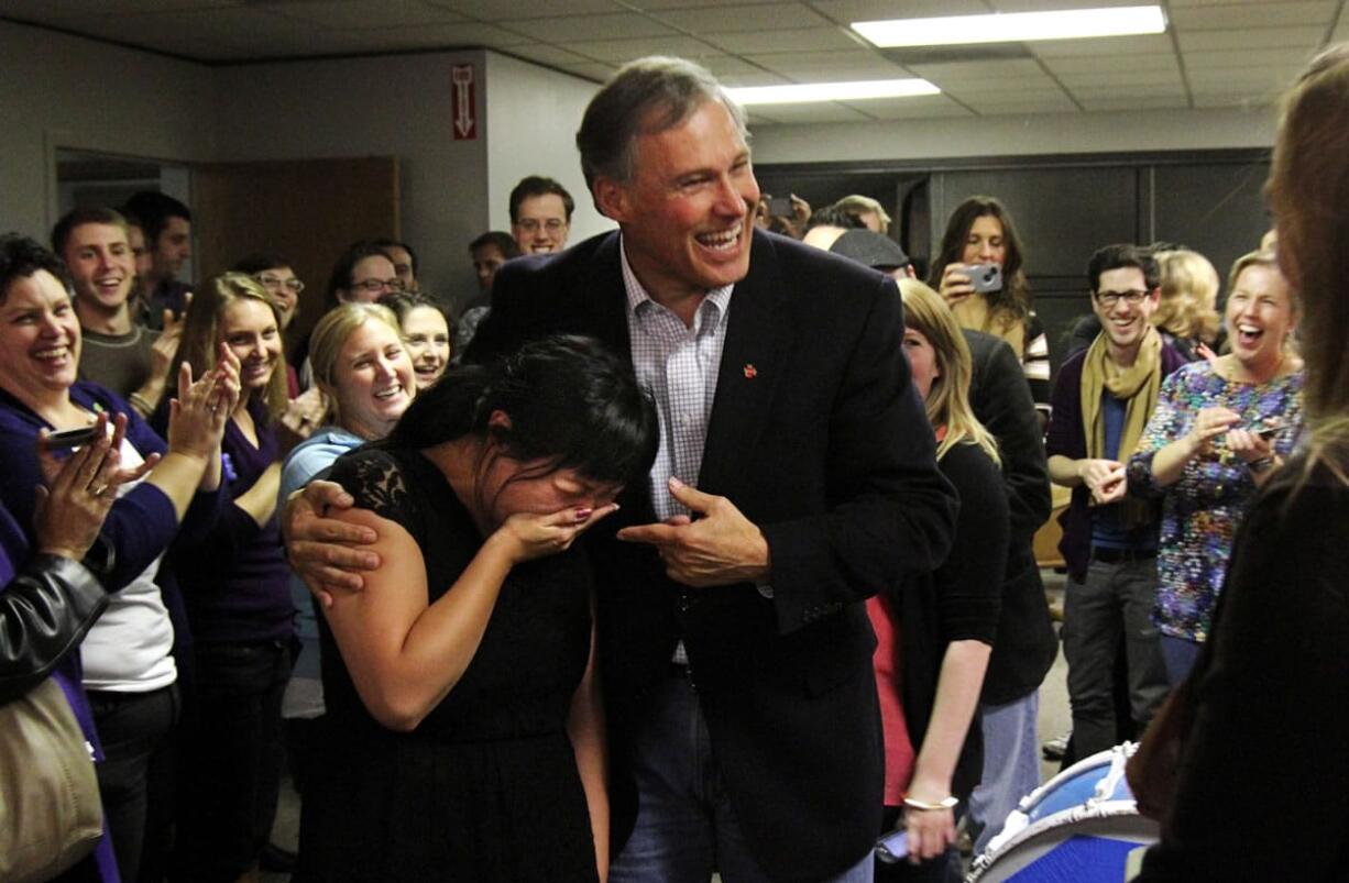 Jay Inslee wins the governor's race in Washington and puts his arm around Unjin Lee, a staffer who  is overcome with emotion that the race is finally resolved Friday.