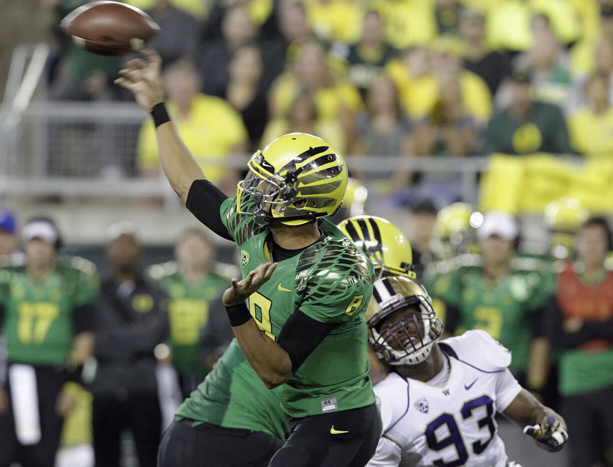 Oregon quarterback Marcus Mariota, left, throws as Washington defender Andrew Hudson (93) tries to close in.