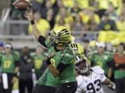 Oregon quarterback Marcus Mariota, left, throws as Washington defender Andrew Hudson (93) tries to close in.