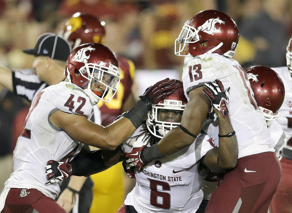 Washington State cornerback Damante Horton, middle, celebrates his interception with teammates Cyrus Coen, left, and Darryl Monroe during the second half of an NCAA college football game against Southern California in Los Angeles, Saturday, Sept. 7, 2013.