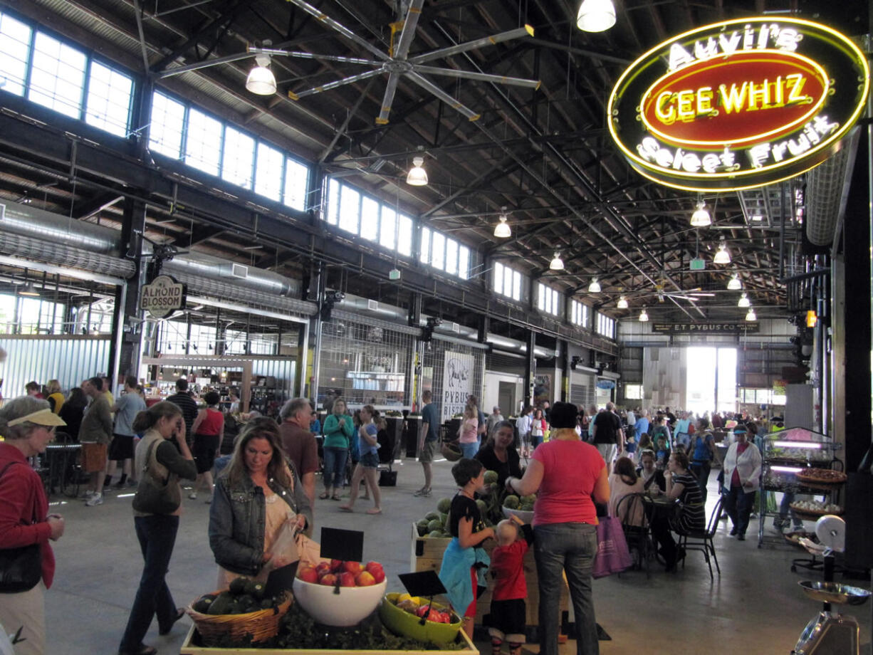 Shoppers wander through the new Pybus Public Market in Wenatchee. The market houses about 20 year-round restaurants and shops, including fruit stands, meat and seafood shops and specialty stores featuring flavored vinegars and oils, tea, beer, wine, nuts and home decor items.