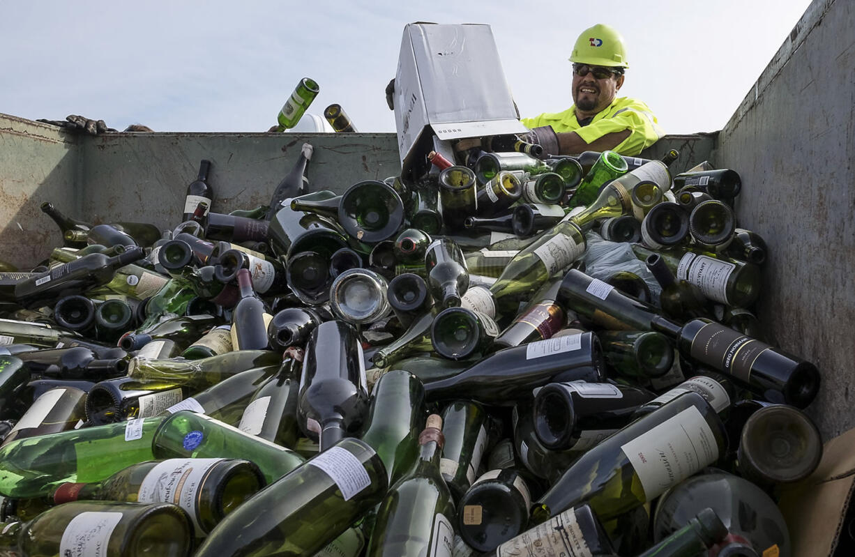 Kevin Benavides, left, and Isidoro Guerra and with Texas Disposal Systems dump more than 500 counterfeit or unsellable wine bottles into a dumpster to be destroyed by the US Marshals Asset Forfeiture Division at the Texas Disposal Systems recycling and compost facility in Austin, Texas, on Thursday. The wine is from the Rudy Kurniawan case, the man convicted of fraud in federal court in 2013 for producing and selling millions of dollars of counterfeit wine.