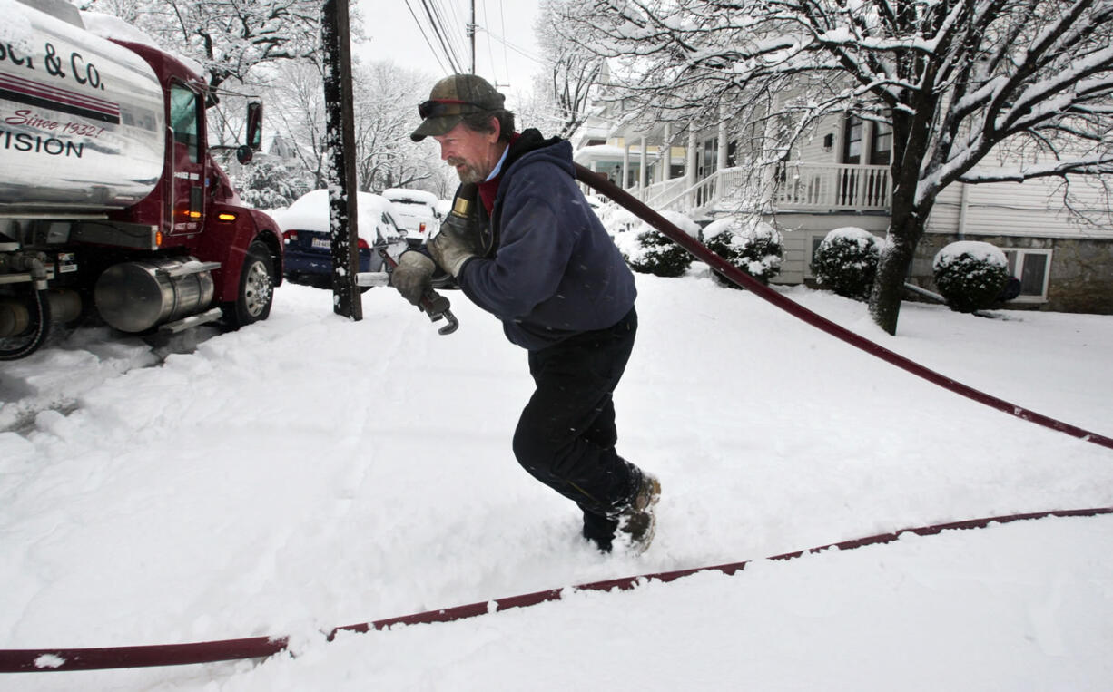 Delivery truck driver Donald Whitacre, of Gore, Va., returns to his truck after pumping 200-gallons of home heating oil into a customer's tank during heavy snowfall in Winchester, Va. Chillier weather and slightly higher fuel prices may make the winter of 2013-14, the most expensive one in three years for U.S.