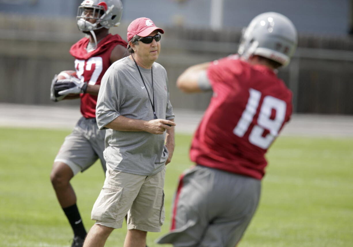Washington State head coach Mike Leach, center, watches wide receivers Brett Bartolone, right, and Bobby Ratliff, left, run drills during on the first day of fall camp last week.