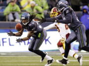 Seattle Seahawks' Richard Sherman, left, intercepting a pass intended for Washington Redskins' Santana Moss, is scheduled to appear in Vancouver in July as part of the &quot;12 Tour&quot; stops throughout the Pacific Northwest.