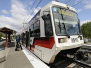 Passengers board a TriMet Max light rail train at the Delta Park/Vanport light rail transit station.