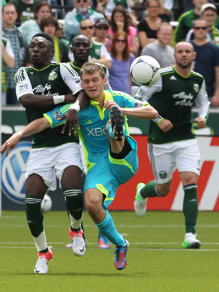 Portland Timbers' Kalif Alhassan, left, defends against Seattle Sounders' Cordell Cato, center, in the first half  Sunday.