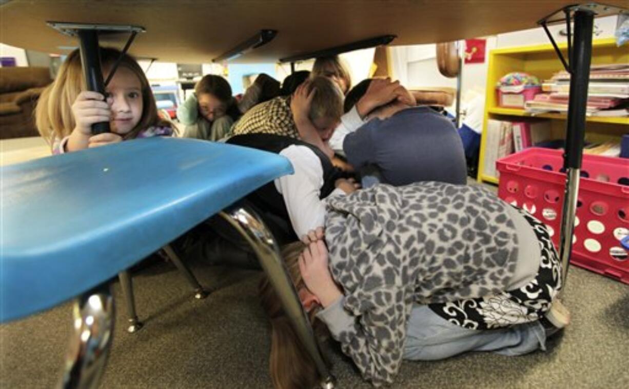 Jaely John, 7, left, a student at Twin Lakes Elementary School in Federal Way, takes shelter under a table with other students as they take part in an earthquake drill Thursday.