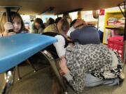 Jaely John, 7, left, a student at Twin Lakes Elementary School in Federal Way, takes shelter under a table with other students as they take part in an earthquake drill Thursday.