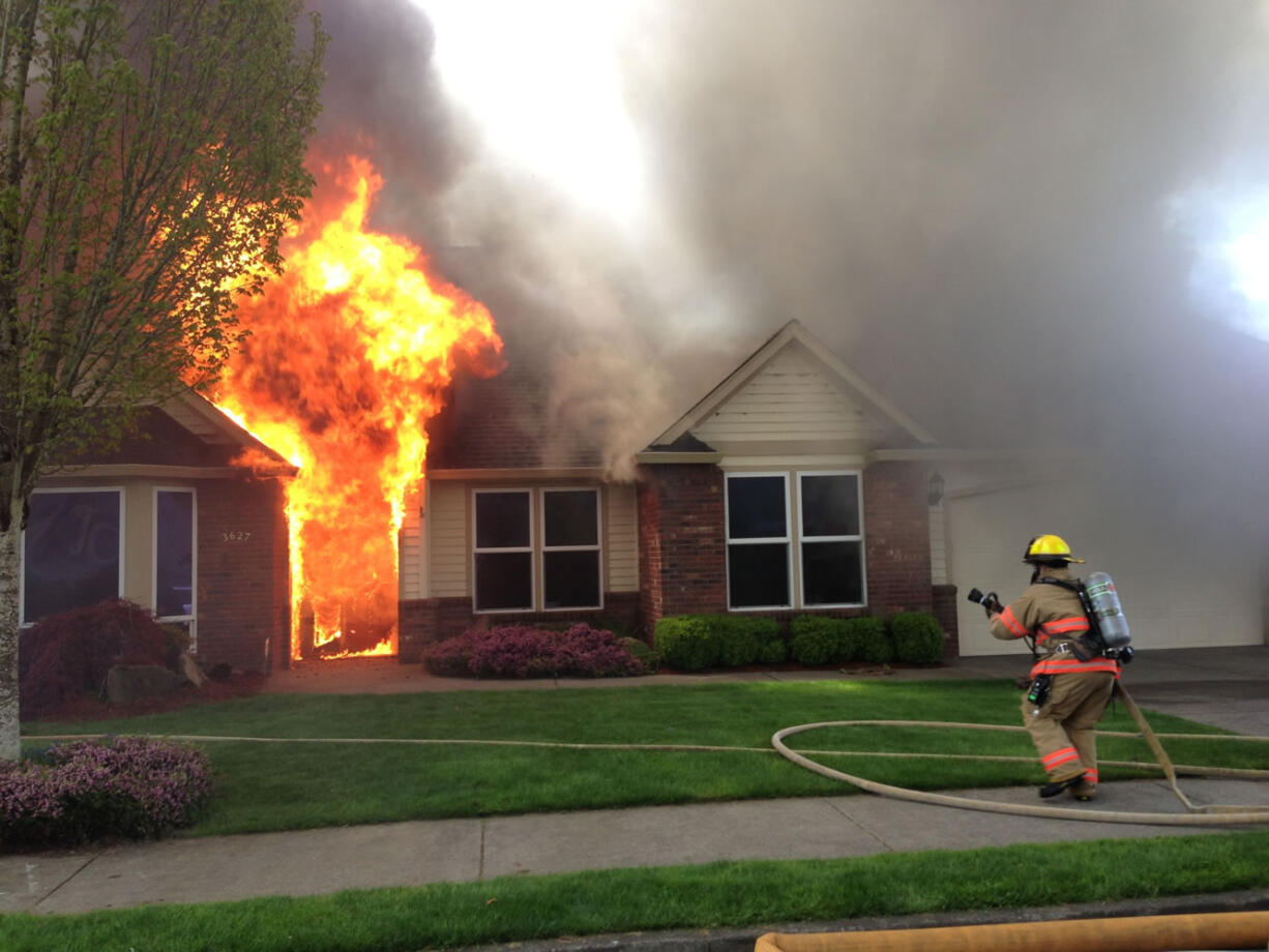 A Camas firefighter prepares to extinguish flames that destroyed a home on Northwest Sierra Drive in Camas on Tuesday.