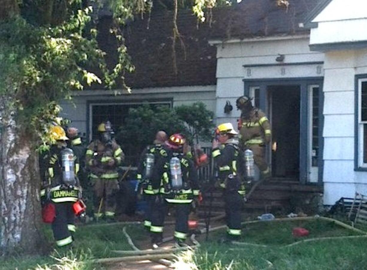 Firefighters work outside a house on the 14100 block of Northeast 72nd Avenue that caught fire on Saturday.