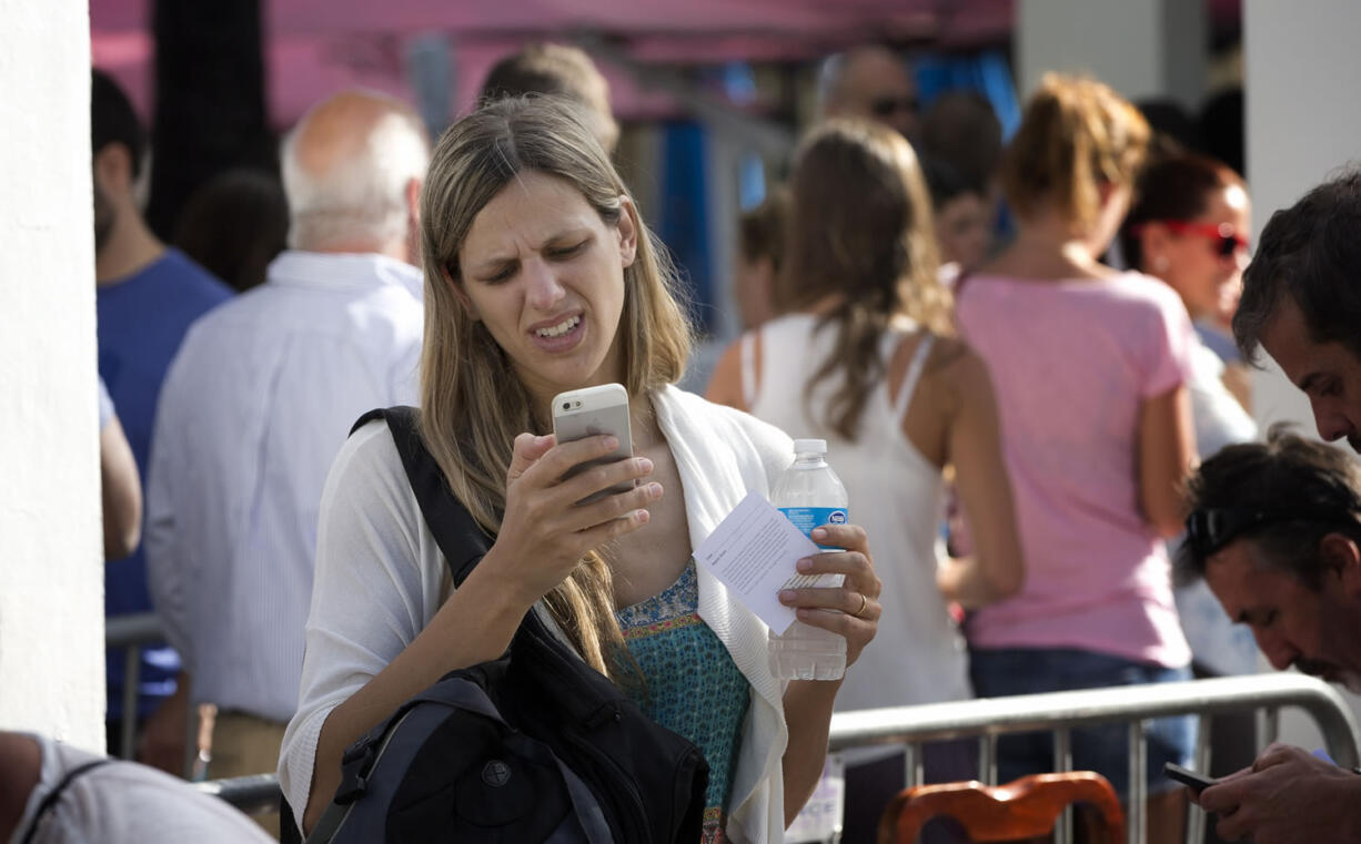 A woman stands in line outside the Apple Store on Lincoln Road in Miami Beach, Fla., on Friday.