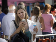 A woman stands in line outside the Apple Store on Lincoln Road in Miami Beach, Fla., on Friday.