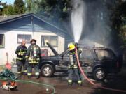 Firefighters from Vancouver Fire Department finish extinguishing the blaze that destroyed a vehicle near East 36th Street and O Street in Vancouver.