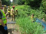 Fire crews work to remove an injured occupant of a pickup that went off Lucia Falls Road near Yacolt on Saturday.