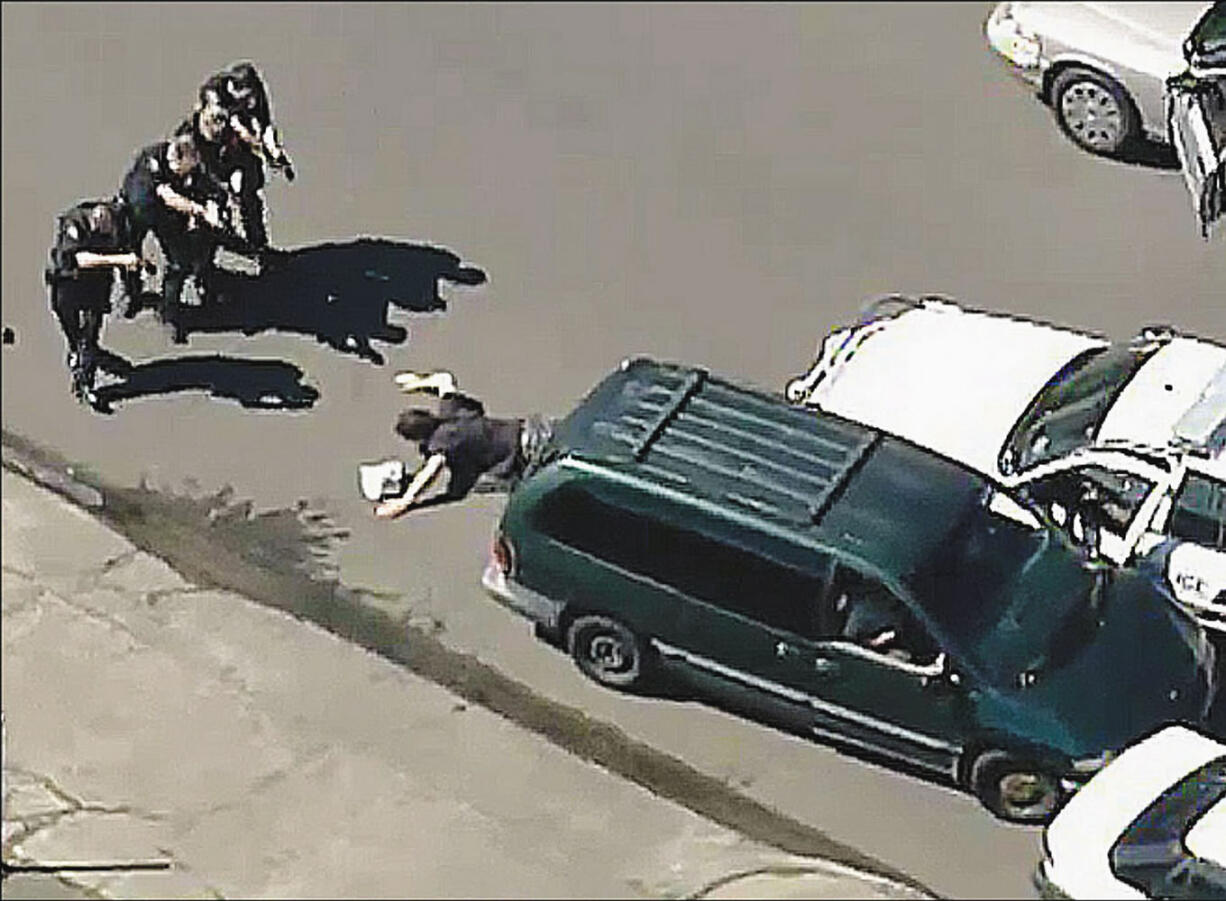 Robbery suspect Brent Woodall cast aside a Taser-like device (behind police officers) before surrendering to Portland police officers in this June 20 still image courtesy of KATU.