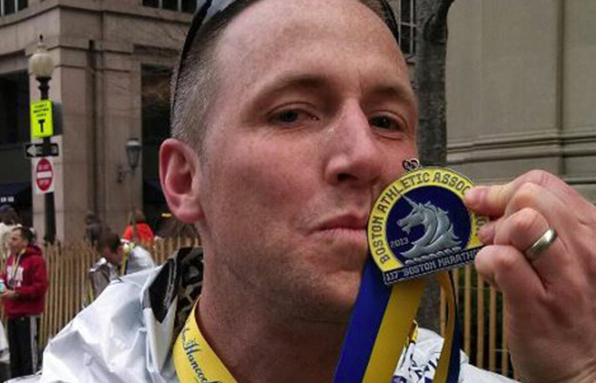 Vancouver resident Micah Rice, The Columbian's news editor, kisses his medal after completing the Boston Marathon on Monday. Rice is among nearly 30 runners from Clark County who participated in the race.