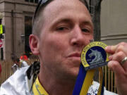 Vancouver resident Micah Rice, The Columbian's news editor, kisses his medal after completing the Boston Marathon on Monday. Rice is among nearly 30 runners from Clark County who participated in the race.