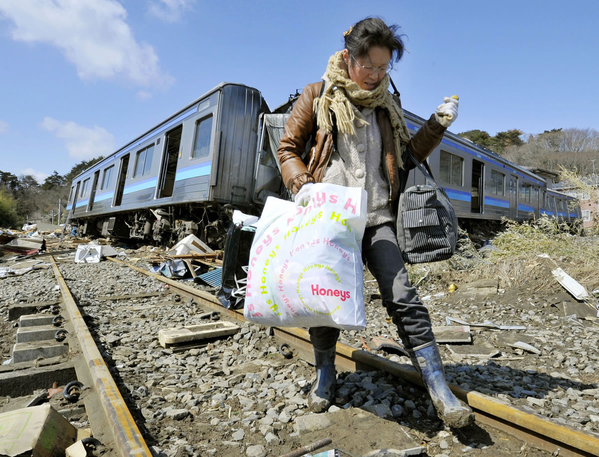 Kyodo News files
A woman walks along a railroad track, passing tsunami-wrecked train cars in Higashimatsushima, Miyagi Prefecture, Japan, after the 9.0 earthquake and tsunami devastated that region in 2011. The Pacific Northwest could see similar damage if the Cascadia fault ruptures.