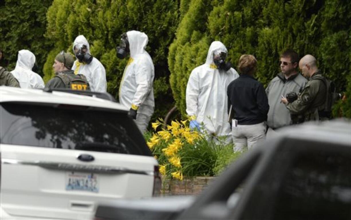 During the execution of a search warrant, members of the Joint Federal Haz-Mat Team, FBI, and local law enforcement gather in front of the Osmun Apartments on Saturday, May 18, 2013 in Spokane. The search warrant is in connection with ricin-laced letters intercepted at a Post Office facility in Spokane earlier in the week.