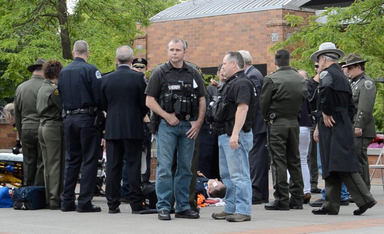 A group of police officers surround Vancouver Interim Police Chief Chris Sutter as he is treated by paramedics outside the Clark County Public Service Center.