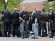 A group of police officers surround Vancouver Interim Police Chief Chris Sutter as he is treated by paramedics outside the Clark County Public Service Center.