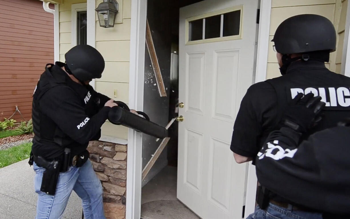 Police officers serve a search warrant on a house on Southeast 191st Avenue as part of a series of 56 raids conducted in Operation Gang Green last October.