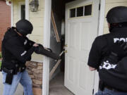 Police officers serve a search warrant on a house on Southeast 191st Avenue as part of a series of 56 raids conducted in Operation Gang Green last October.