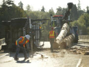 Washington State Department of Transportation workers and tow crews use heavy equipment to remove logs from an overturned log truck on an onramp Wednesday September 12, 2012 in Vancouver, Washington.