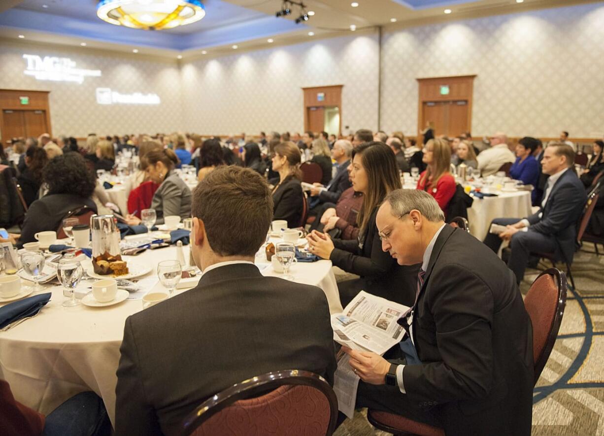 Mark Martel of Martel Wealth Advisors, right, looks over an informational pamphlet while joining a packed crowd Thursday morning, Jan. 21, 2016 at the Vancouver Hilton.