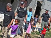 Joe Anfuso, from left, and Forward Edge International team members Nick Rogers and Bob Craddock walk with a group of children during a 2010 mission trip to Port-au-Prince.