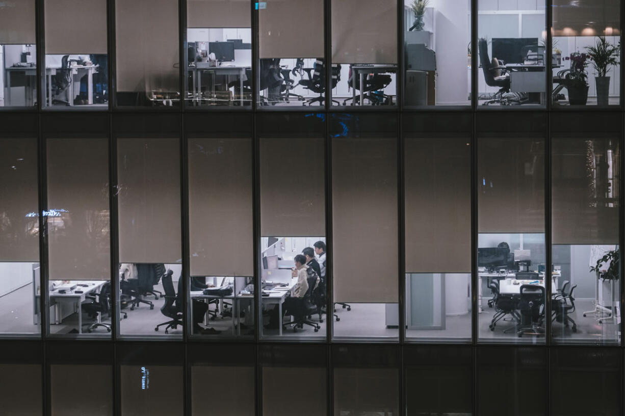 Workers occupy brightly lit offices and do overtime shifts in downtown Seoul on a Thursday night.